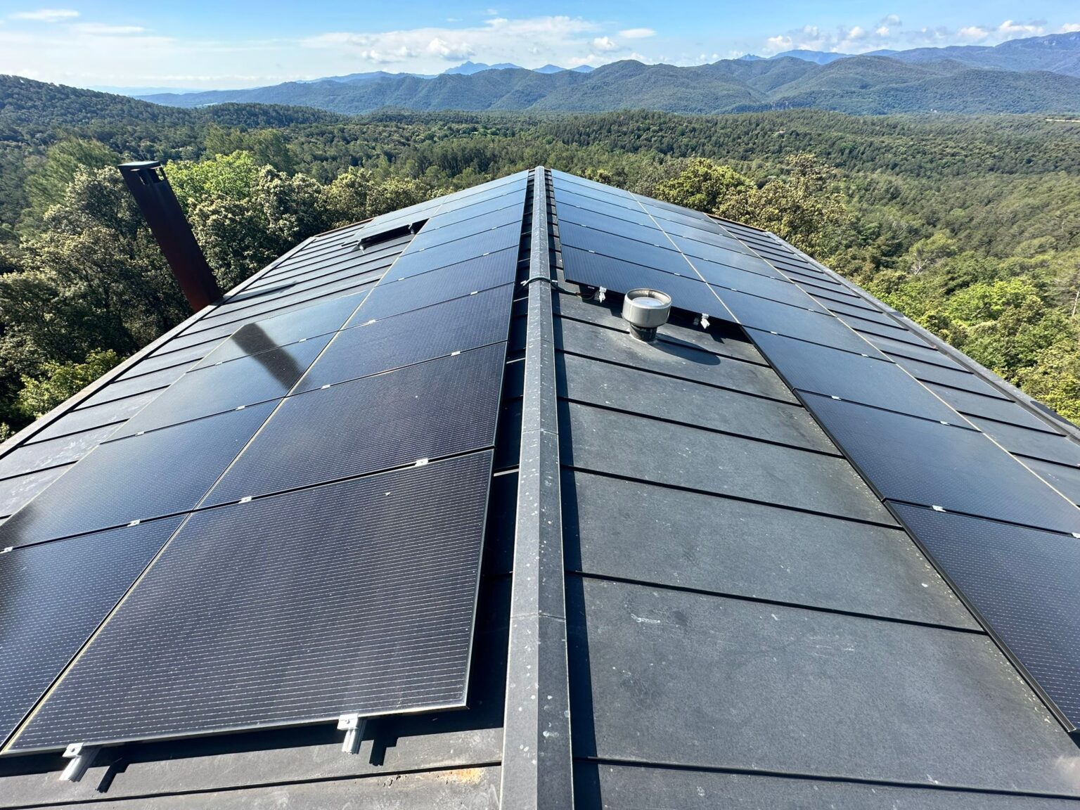 Paneles solares instalados en el tejado de una vivienda rodeada de naturaleza en Barcelona.